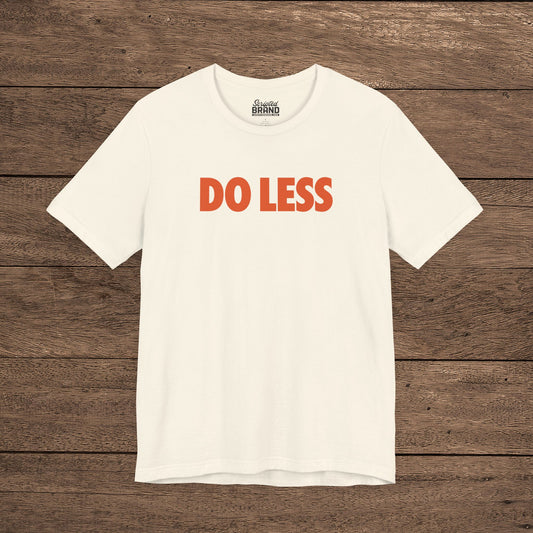 Natural Off-white colored 'Do Less' graphic t-shirt inspired by Shrinking TV show, Bella+Canvas cotton tee with orange type