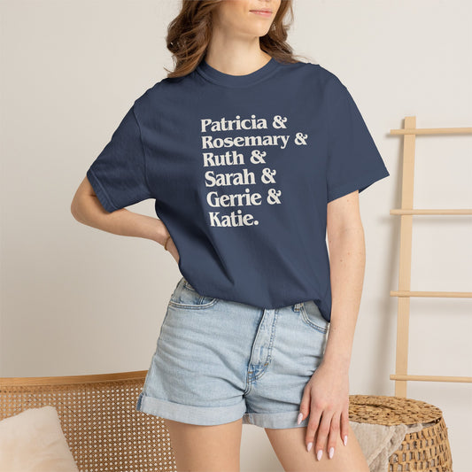 Woman wearing midnight blue Comfort Colors tee listing the women of Widow's Bay: Patricia, Rosemary, Ruth, Sarah, Gerrie, and Katie