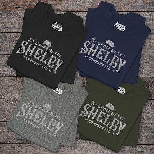 Group of 4 folded soft short-sleeve Bella+Canvas 3001 t-shirts featuring a unique Shelby Company Limited logo graphic from the show Peaky Blinders and movie The Immortal Man, in a vintage distressed style, includes a flat cap and razor blades, designed and sold by ScriptedBrand.