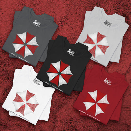 Five folded t-shirts featuring the Umbrella Corp logo from the video game and movie franchise Resident Evil in a vintage distressed style.