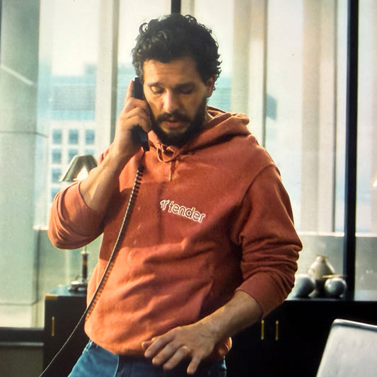 Kit Harington on the phone wearing a Texas Orange Tender logo hoodie sweatshirt in HBO show Industry.