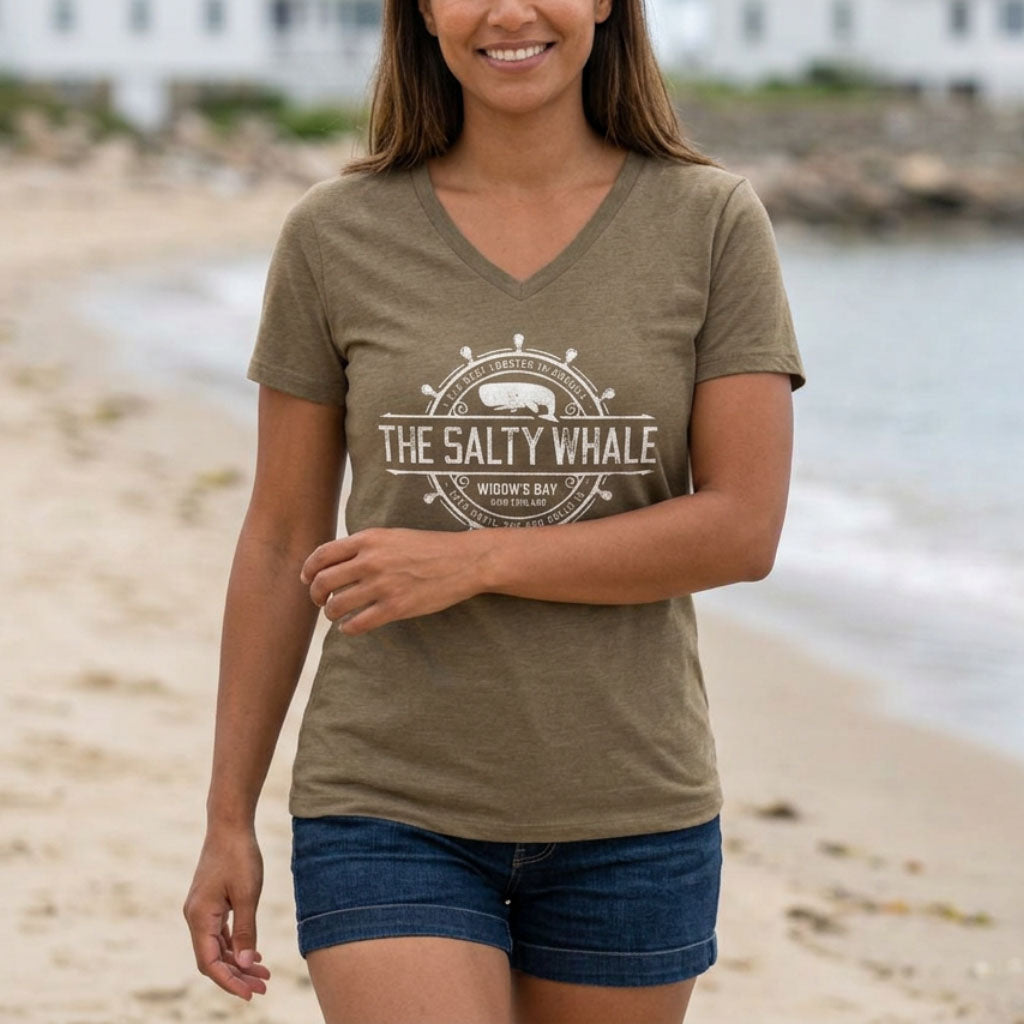 Person on beach wearing Heather olive womens v-neck tee with vintage The Salty Whale nautical crest inspired by Widow's Bay show