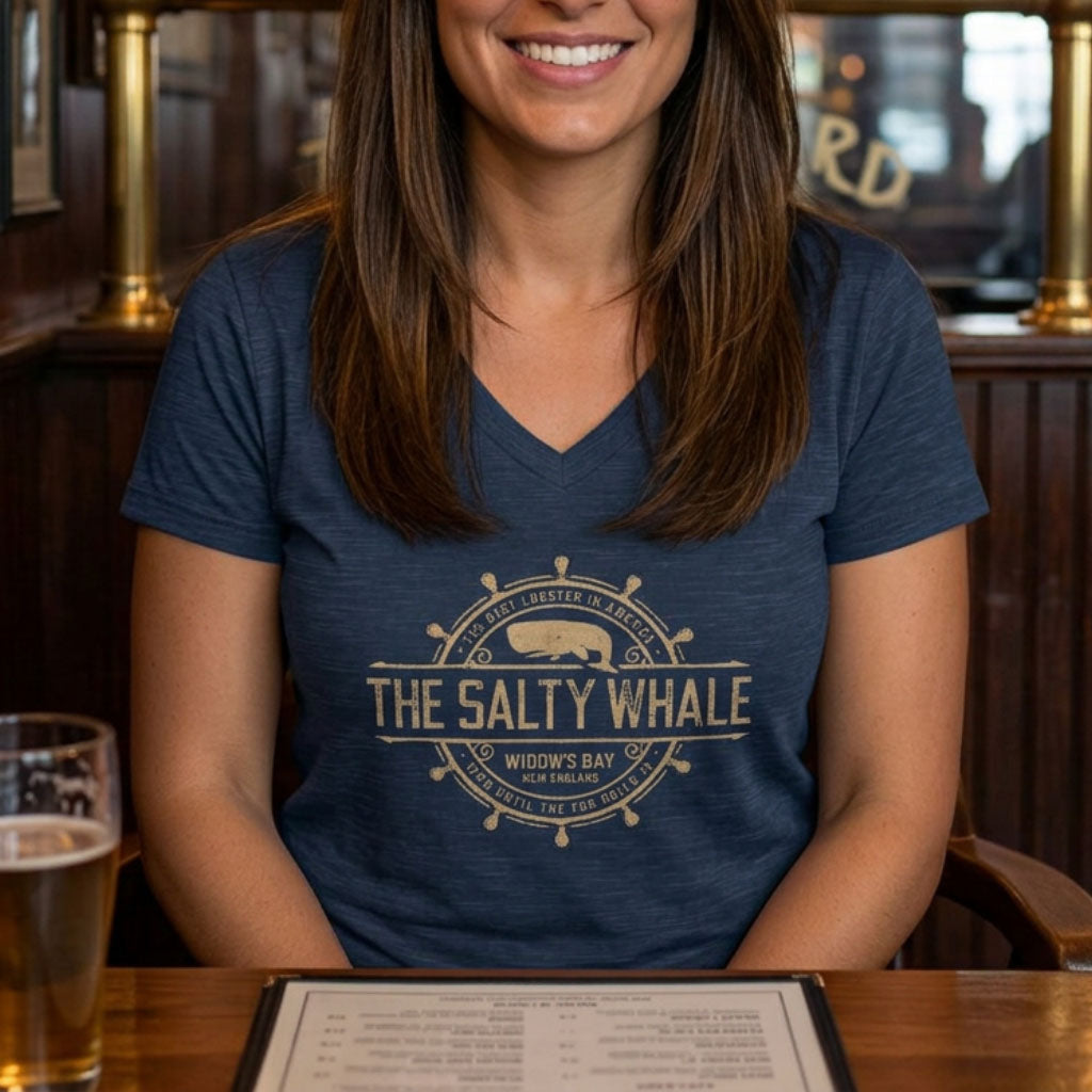 Person wearing Heather navy blue womens v-neck tee with vintage The Salty Whale nautical crest inspired by Widow's Bay show