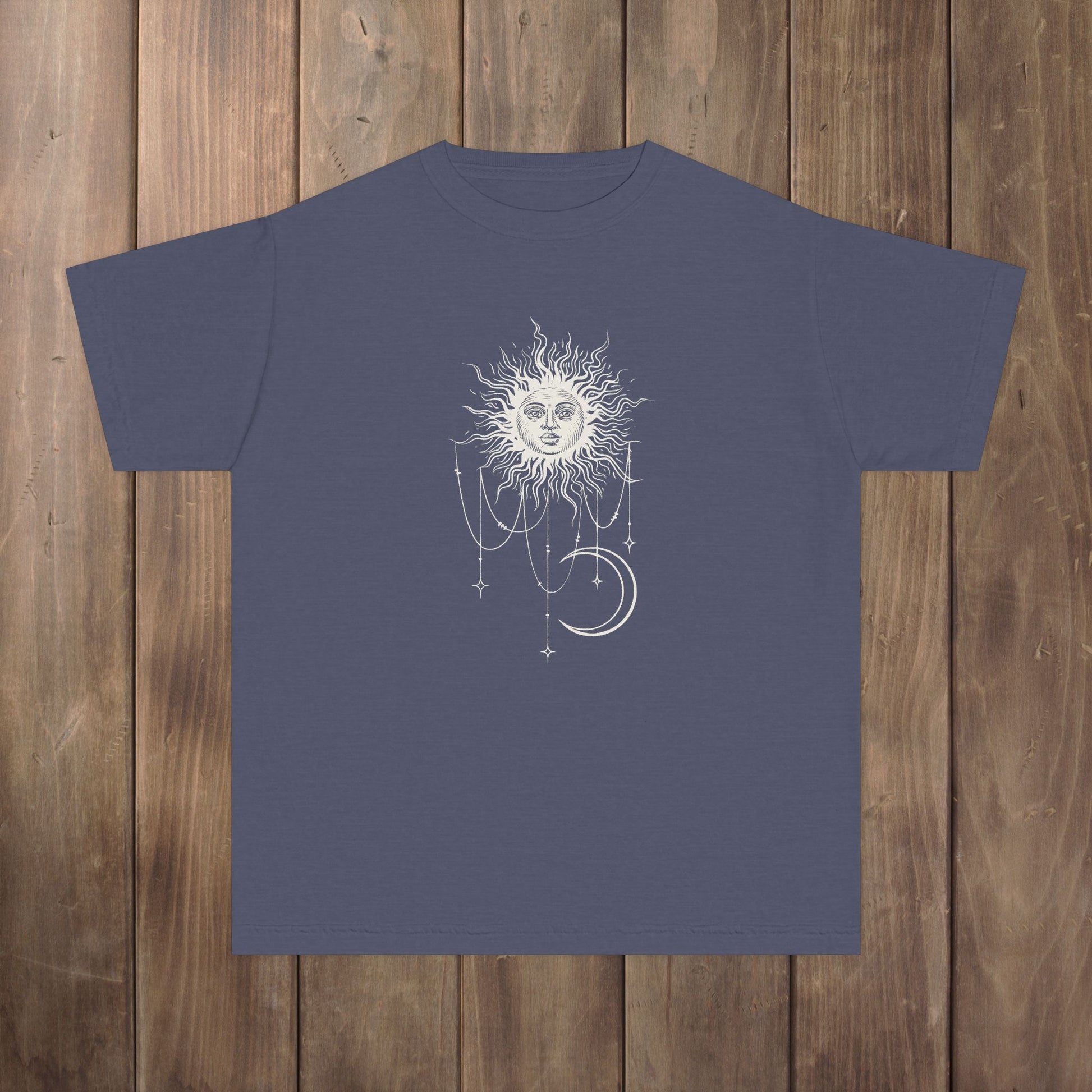 Front of denim blue youth tee with Patricia boho celestial sun, stars, and crescent moon design from Widow's Bay