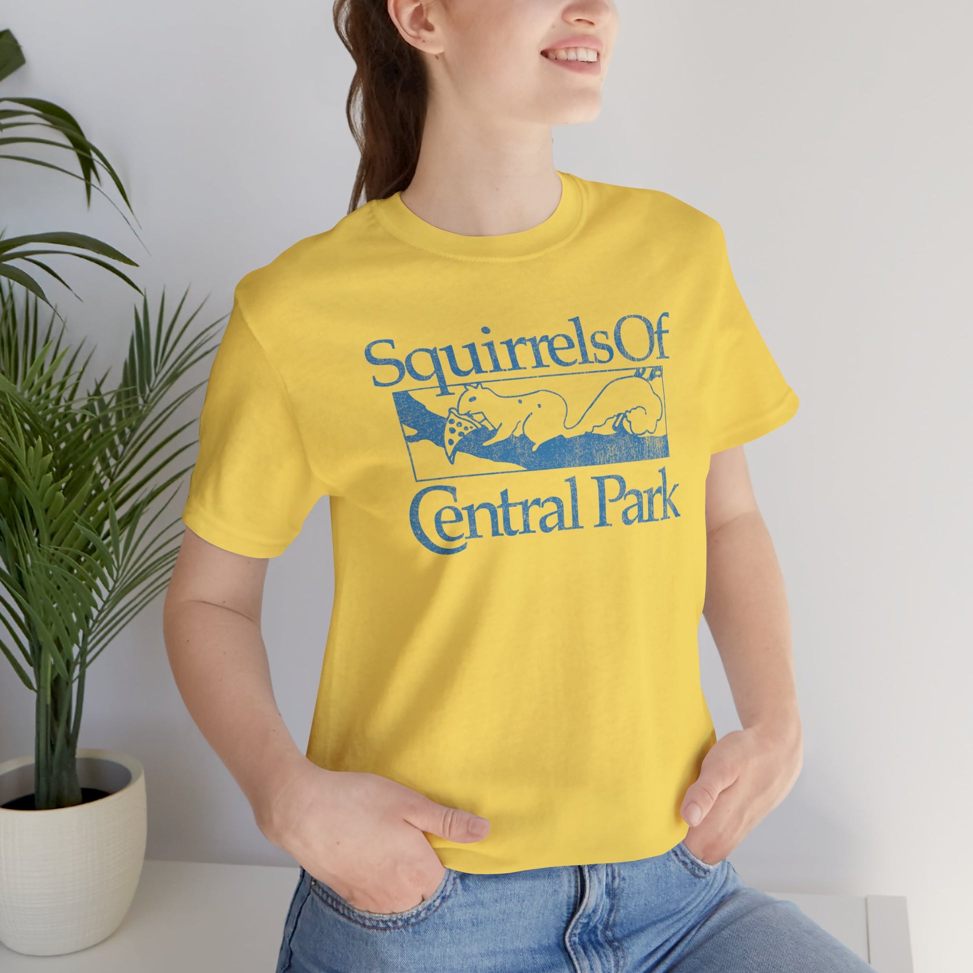 Woman wearing yellow unisex t-shirt with distressed “Squirrels of Central Park” graphic, worn by Eva Garvey in the show Bad Sisters.