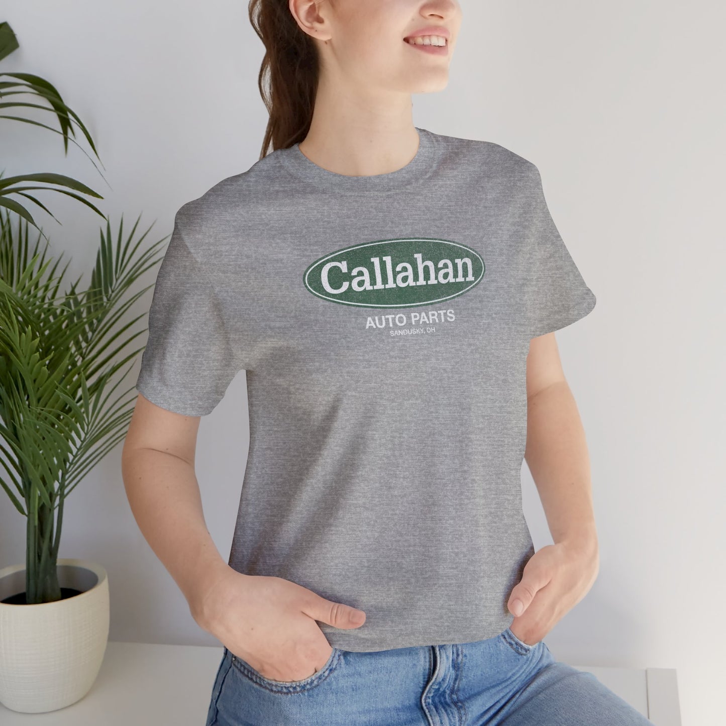 Female model wearing a Heather Gray colored soft t-shirt with the Callahan Auto Parts logo from the movie Tommy Boy in a vintage distressed style.