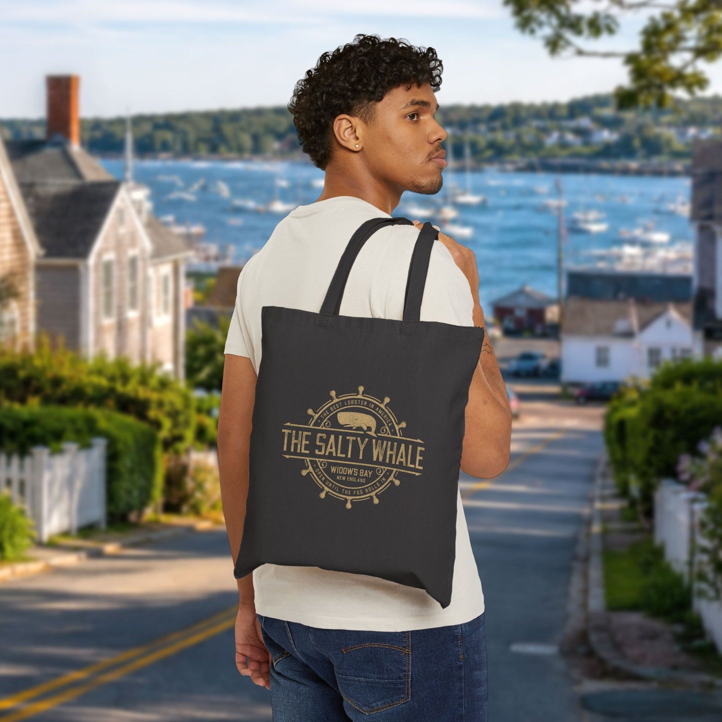 Person carrying black canvas tote bag with vintage The Salty Whale, Widow's Bay TV show nautical grocery shopping