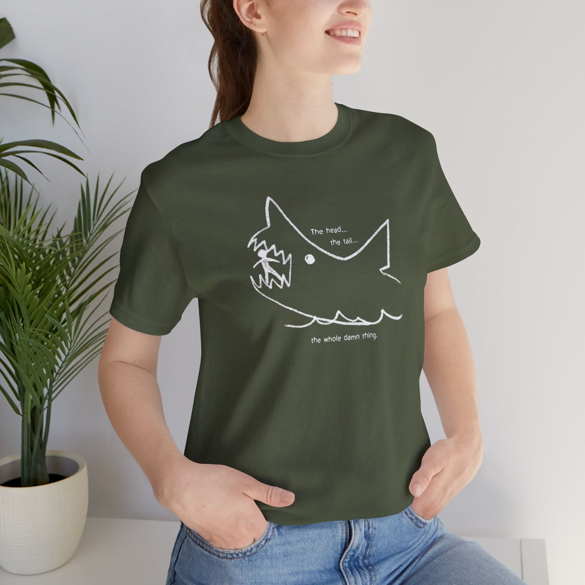 Female model wearing a military green colored soft short-sleeve Bella+Canvas 3001 t-shirt featuring the chalkboard drawing of a shark eating a person, drawn by Quint in the movie Jaws.