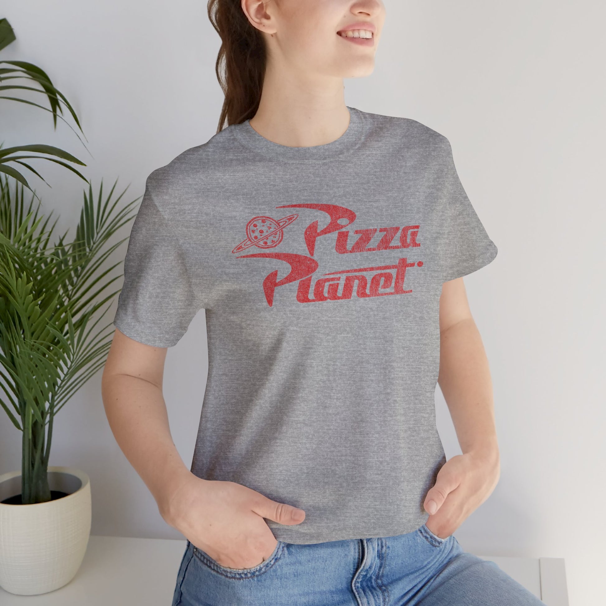 Woman wearing gray t-shirt with distressed red Pizza Planet logo inspired by the Toy Story movies.