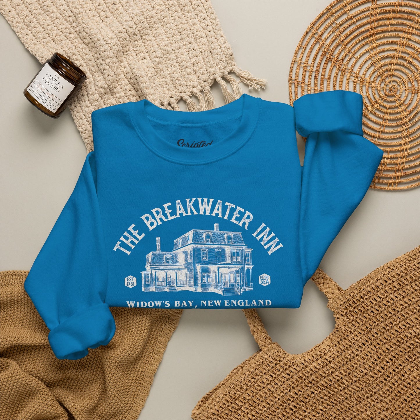 Folded Saphire blue crewneck sweatshirt with Breakwater Inn Widow's Bay New England hotel graphic