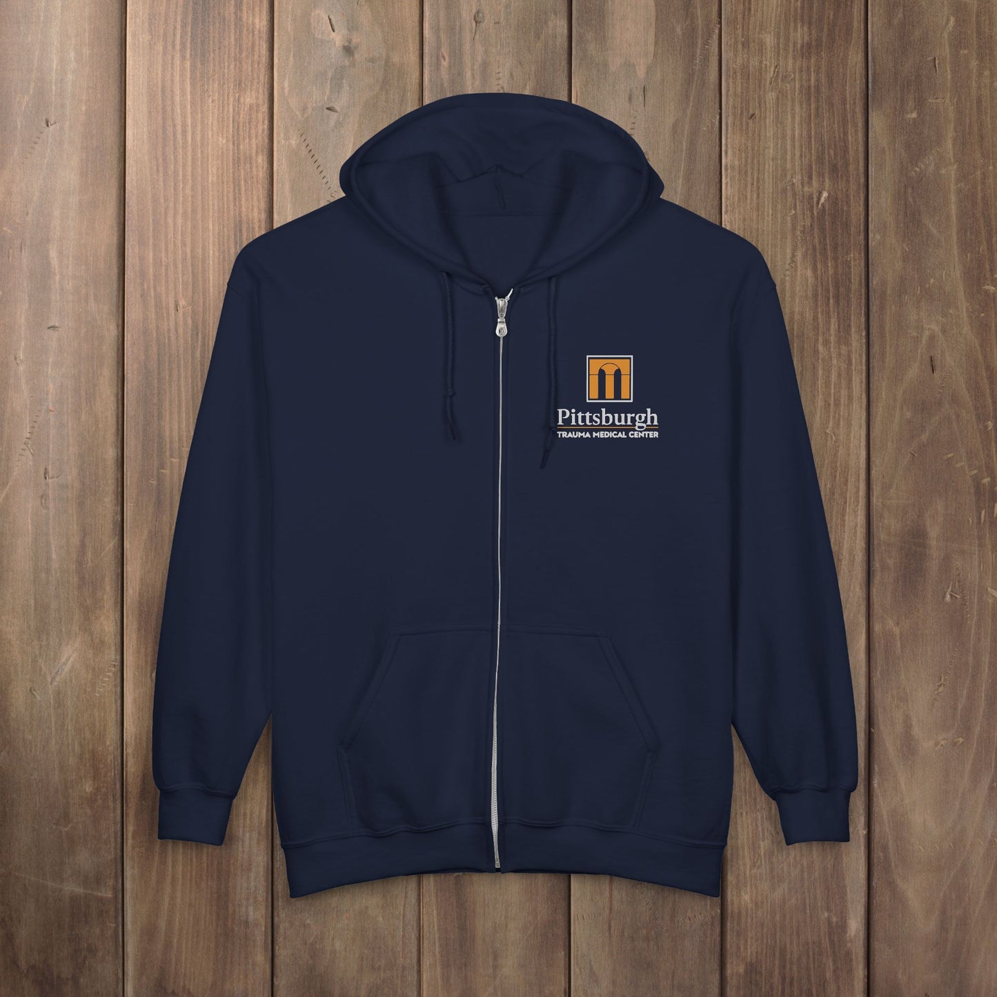Navy blue full-zip hoodie with the Pittsburgh Trauma Medical Center (PTMC) logo from The Pitt, printed on the left chest
