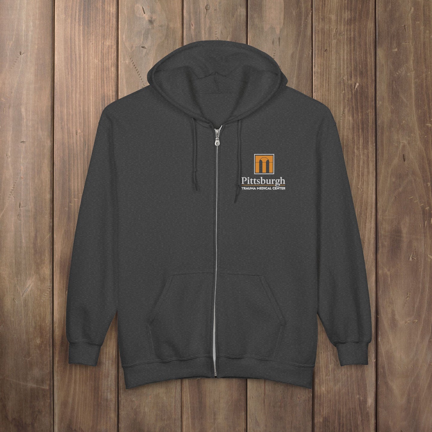 Dark gray heather full-zip hoodie with the Pittsburgh Trauma Medical Center (PTMC) logo from The Pitt, printed on the left chest
