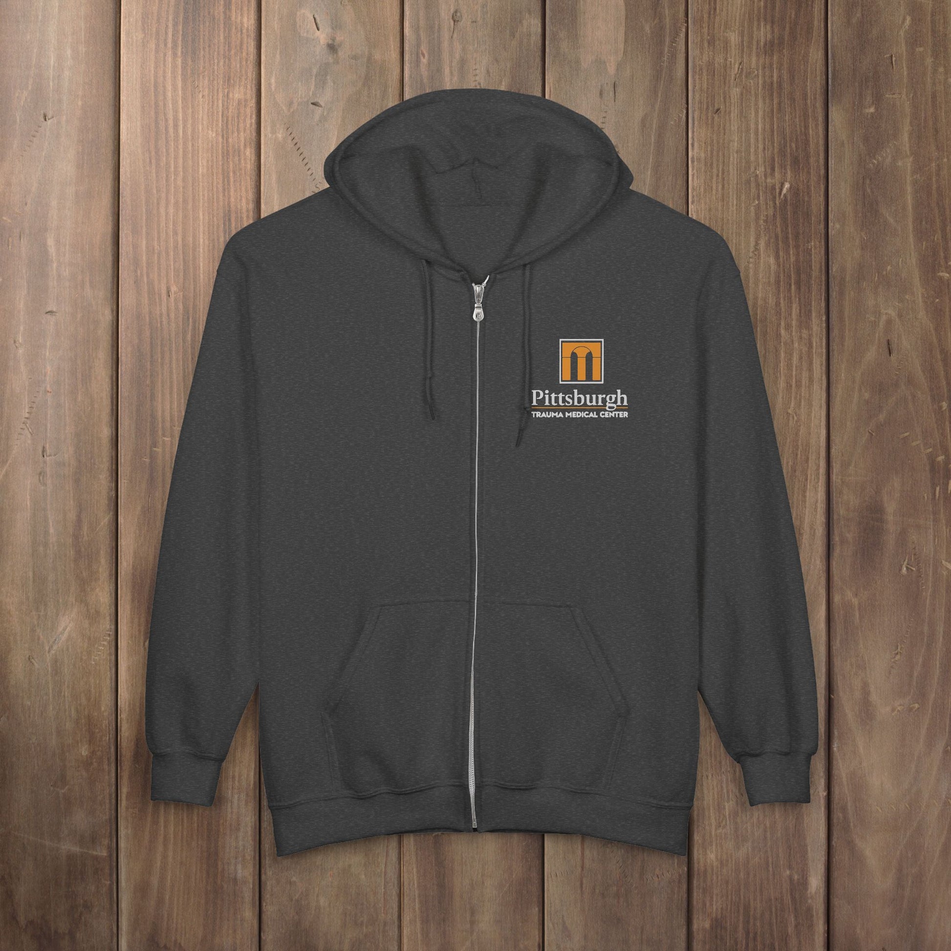 Dark gray heather full-zip hoodie with the Pittsburgh Trauma Medical Center (PTMC) logo from The Pitt, printed on the left chest