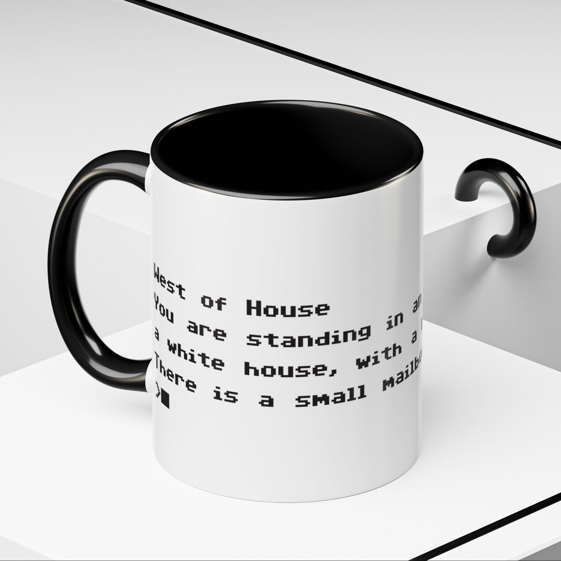 Angled view of 11 oz White ceramic accent mug with black handle and interior, Zork “West of House” opening line text wrapped in black print