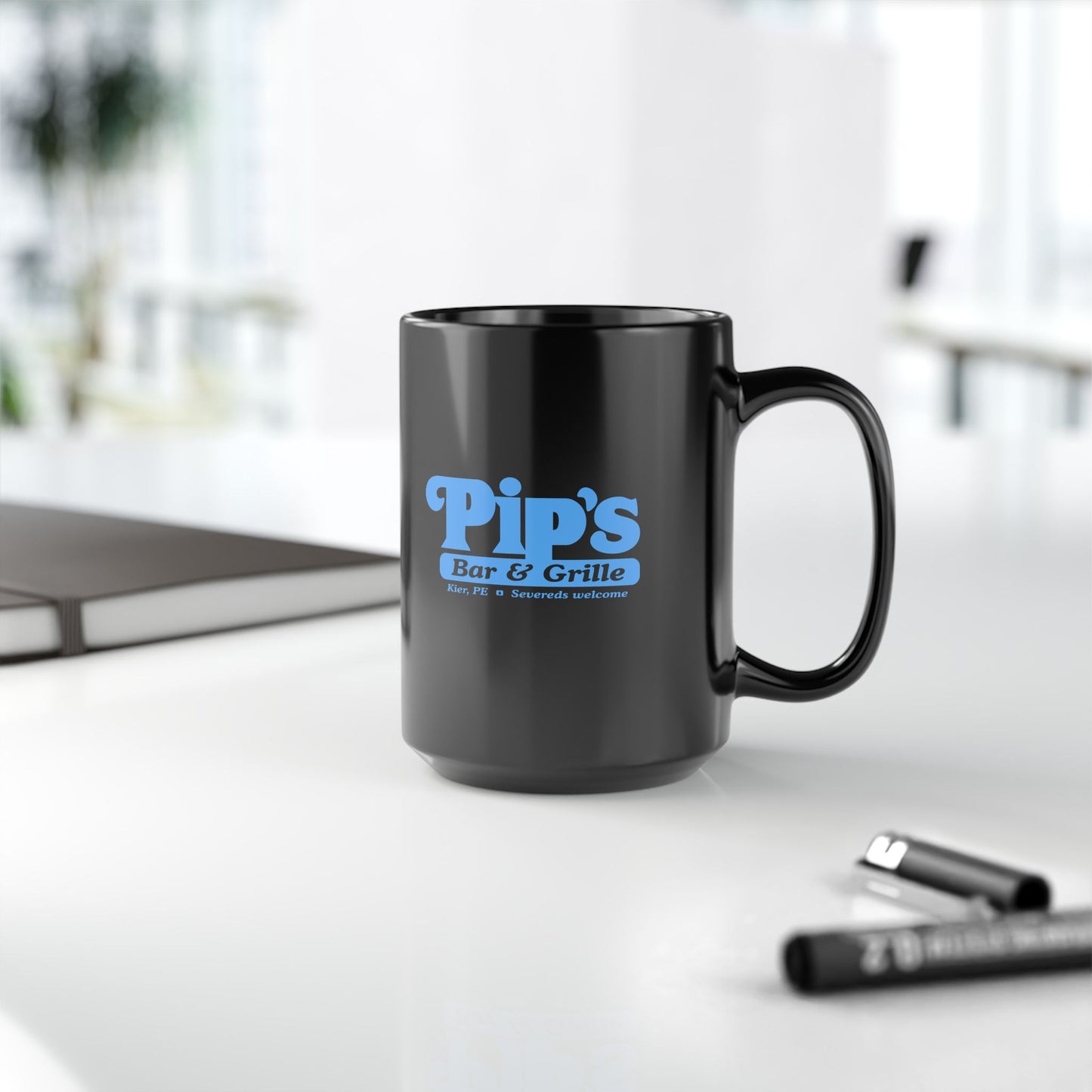 Mockup on a table of a 15 oz Black Ceramic Mug featuring the Pips Bar and Grill logo from the Apple TV show Severance printed on both sides in Lumon Industries blue, sold by ScriptedBrand. 