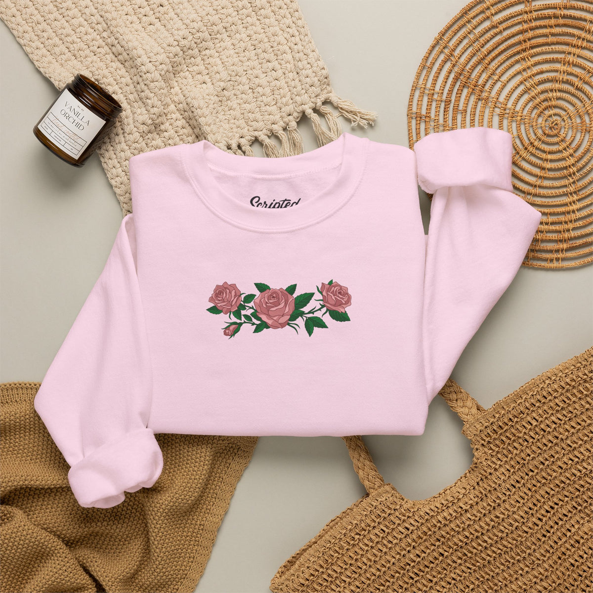 Folded Light pink crewneck sweatshirt with three pink roses and green leaves printed across the chest, inspired by Ruth of Widow's Bay