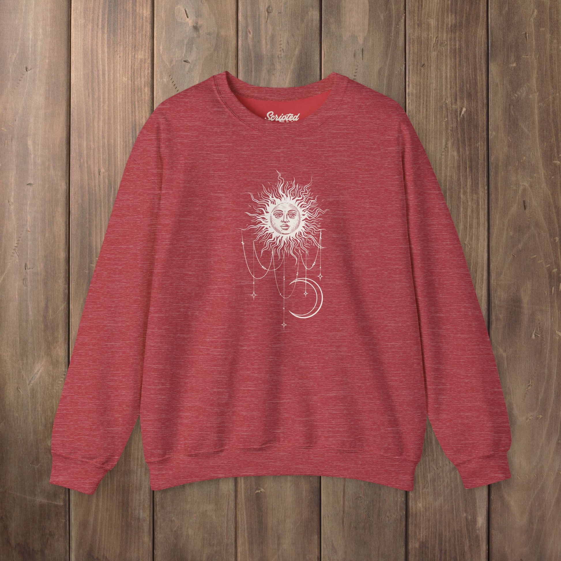 Heather red crewneck sweatshirt with boho celestial sun face, stars, and crescent moon design worn by Patricia in Widow's Bay