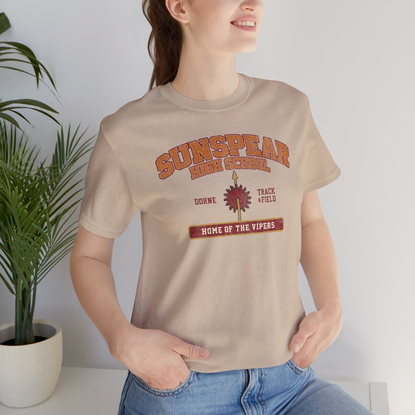 Woman wearing tan Sunspear High School t-shirt with distressed dorne sun graphic inspired by Game of Thrones.