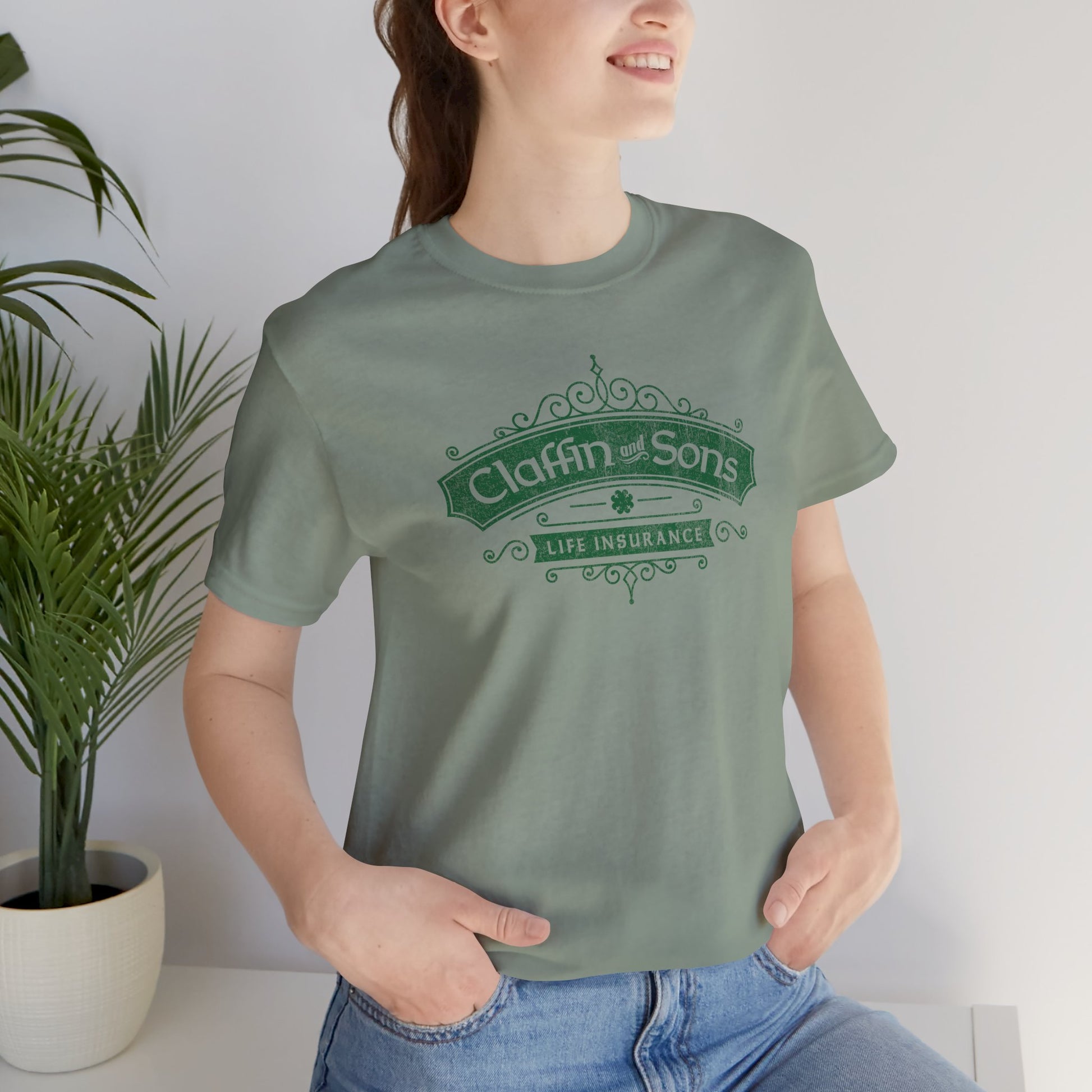 Person wearing Sage Green tee with vintage distressed Claffin and Sons Life Insurance, Bad Sisters TV show graphic