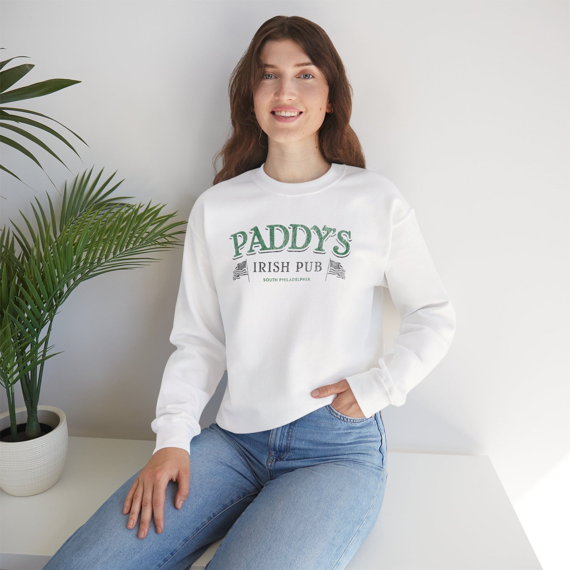 Woman wearing white crewneck Sweatshirt with the Paddy's Pub logo graphic from the TV Show Its Always Sunny in Philadelphia in a vintage style.
