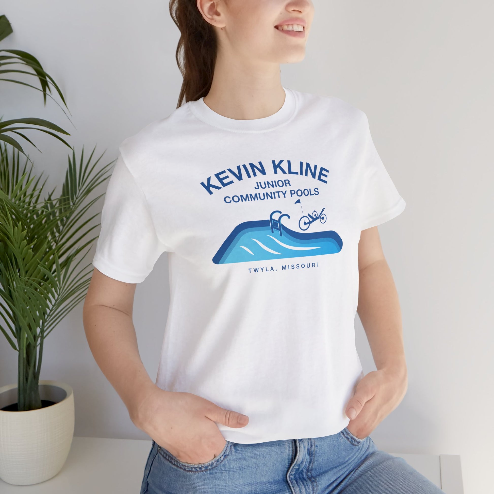 Woman wearing white DTF St. Louis Kevin Kline Junior Community Pools graphic tee with pool and recumbent trike.