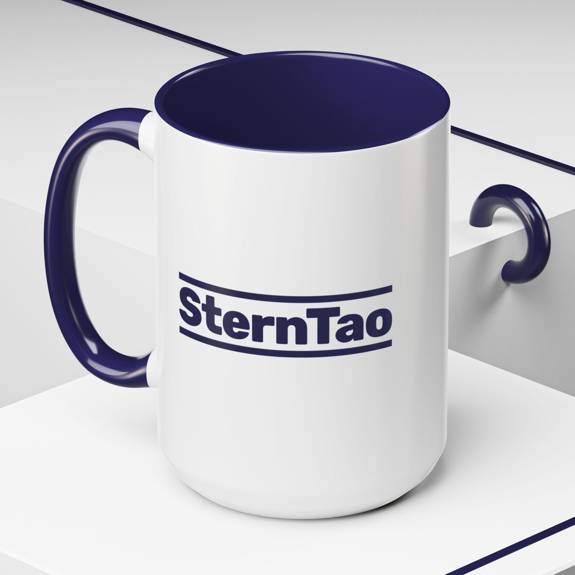 Angled view of SternTao logo navy accent mug inspired by Industry, white ceramic coffee mug with navy handle, two sided print