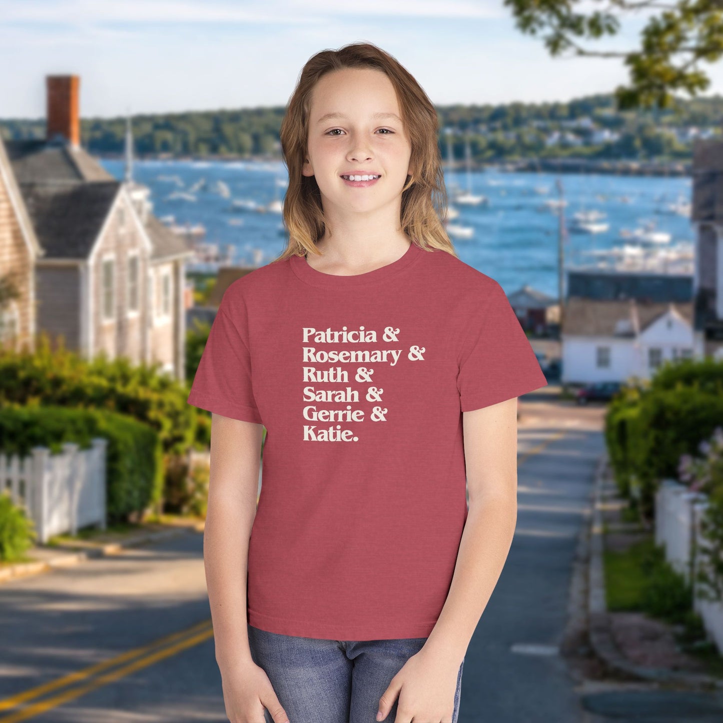 Crimson red youth kids tee with stacked Women of Widow's Bay names in cream type, worn by a girl