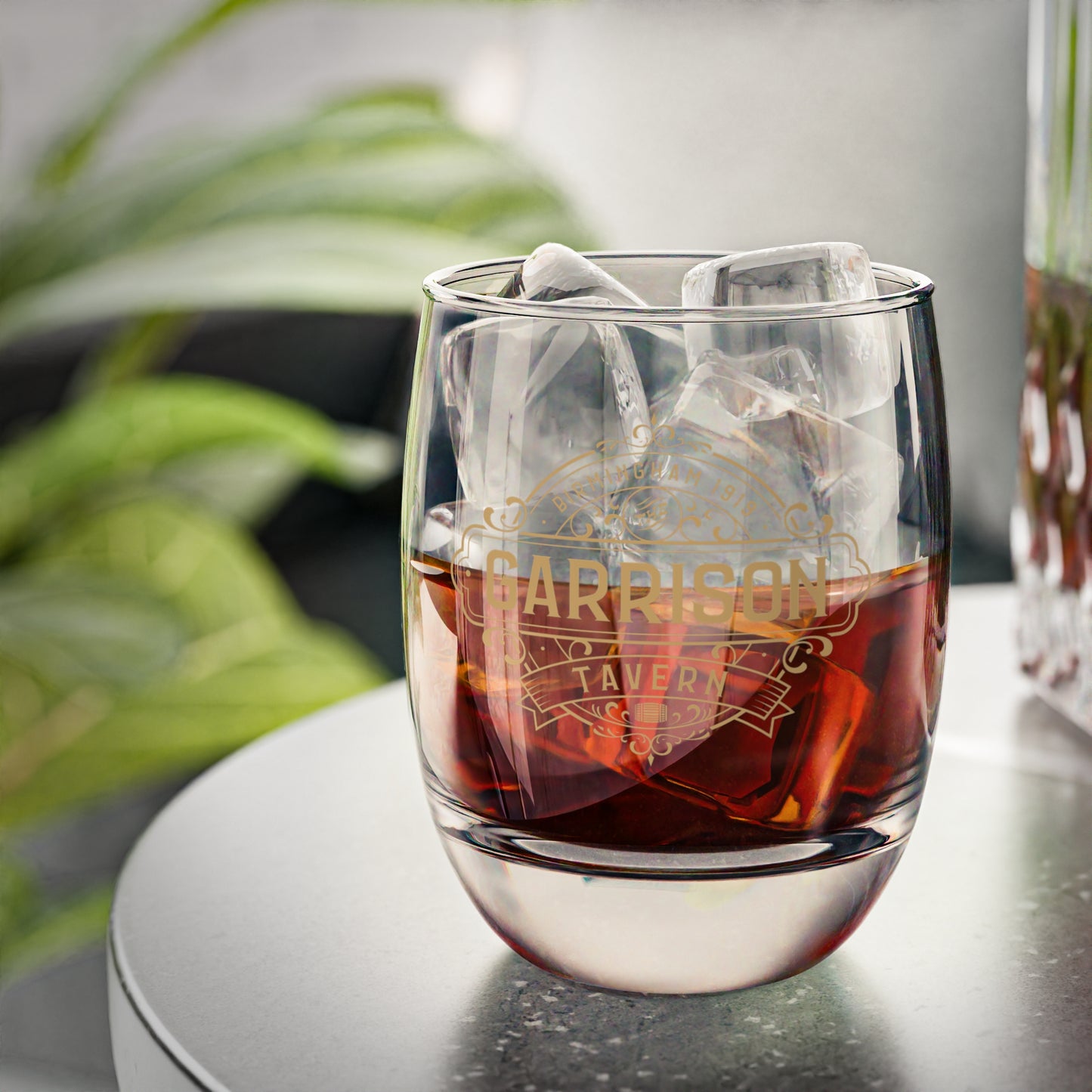 Front view of a half-filled 6 ounce Whiskey Glass featuring the Garrison Tavern Bar Logo Graphic inspired by the TV show and movie Peaky Blinders printed on one side, sold by ScriptedBrand.