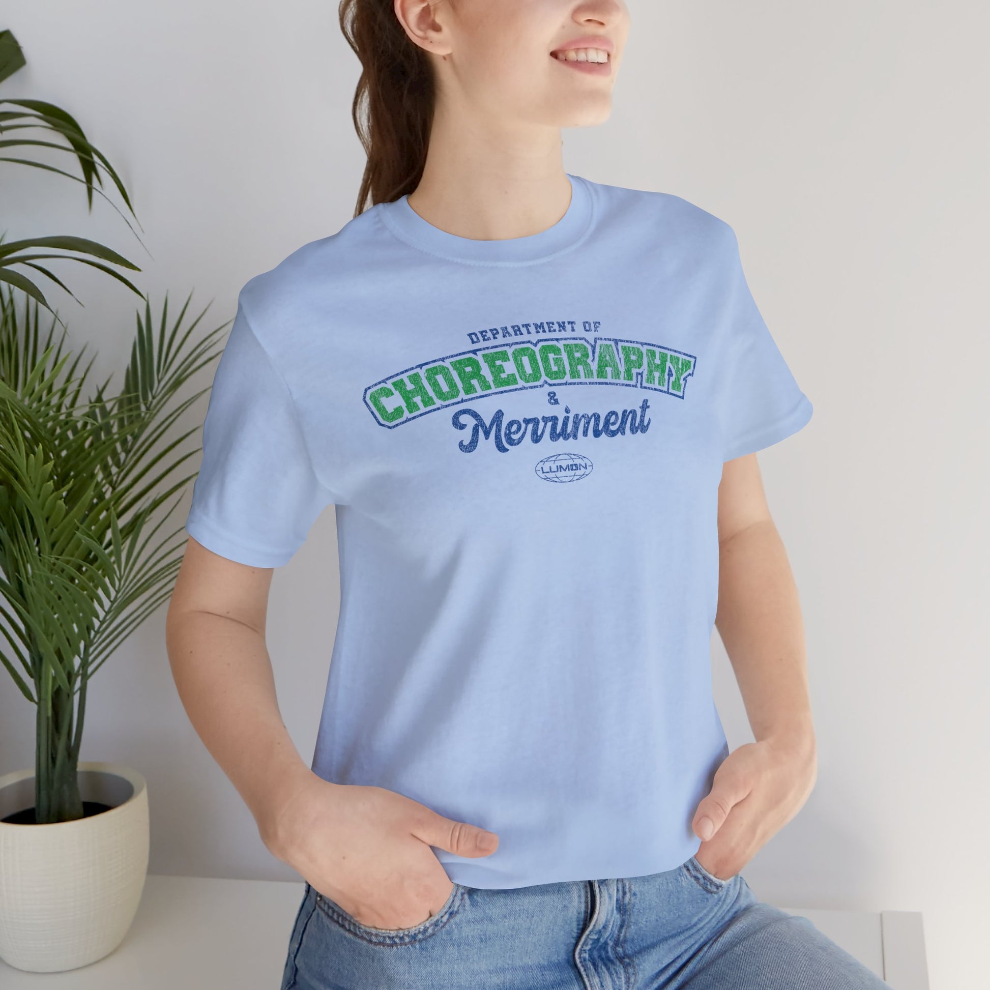 Female model wearing a baby blue Soft Bella+Canvas 3001 short-sleeve t-shirt featuring the Department of Choreography and Merriment logo graphic inspired by the TV show Severance and Lumon Industries in a vintage distressed style, sold by ScriptedBrand.