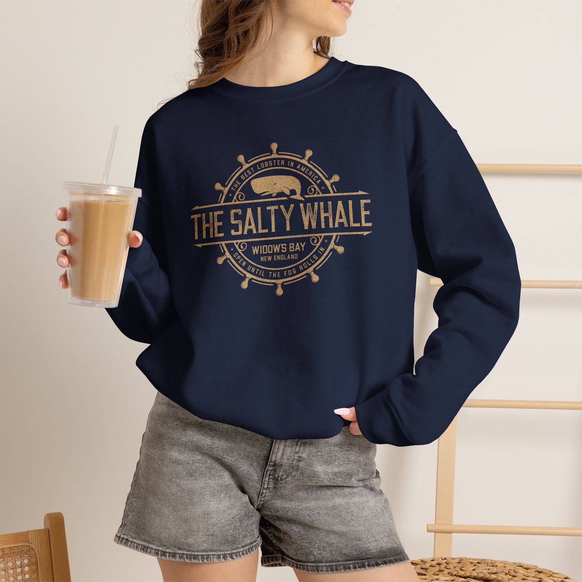 Woman wearing Navy blue Gildan crewneck sweatshirt with the distressed Salty Whale maritime crest logo from TV show Widow's Bay
