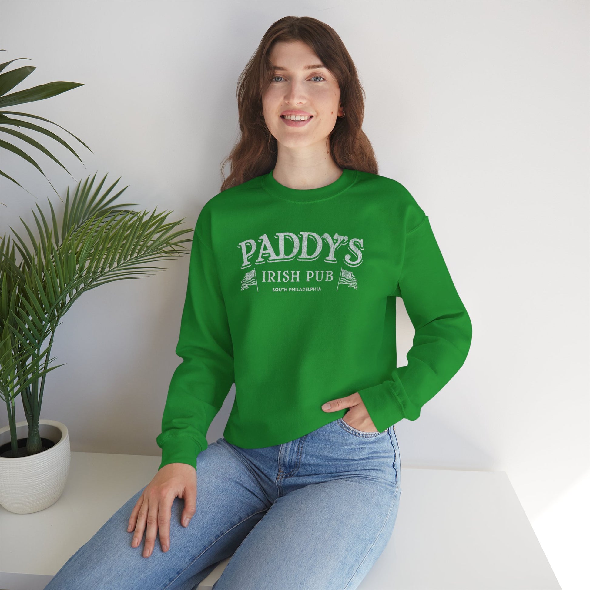 Woman wearing green crewneck Sweatshirt with the Paddy's Pub logo graphic from the TV Show Its Always Sunny in Philadelphia in a vintage style.