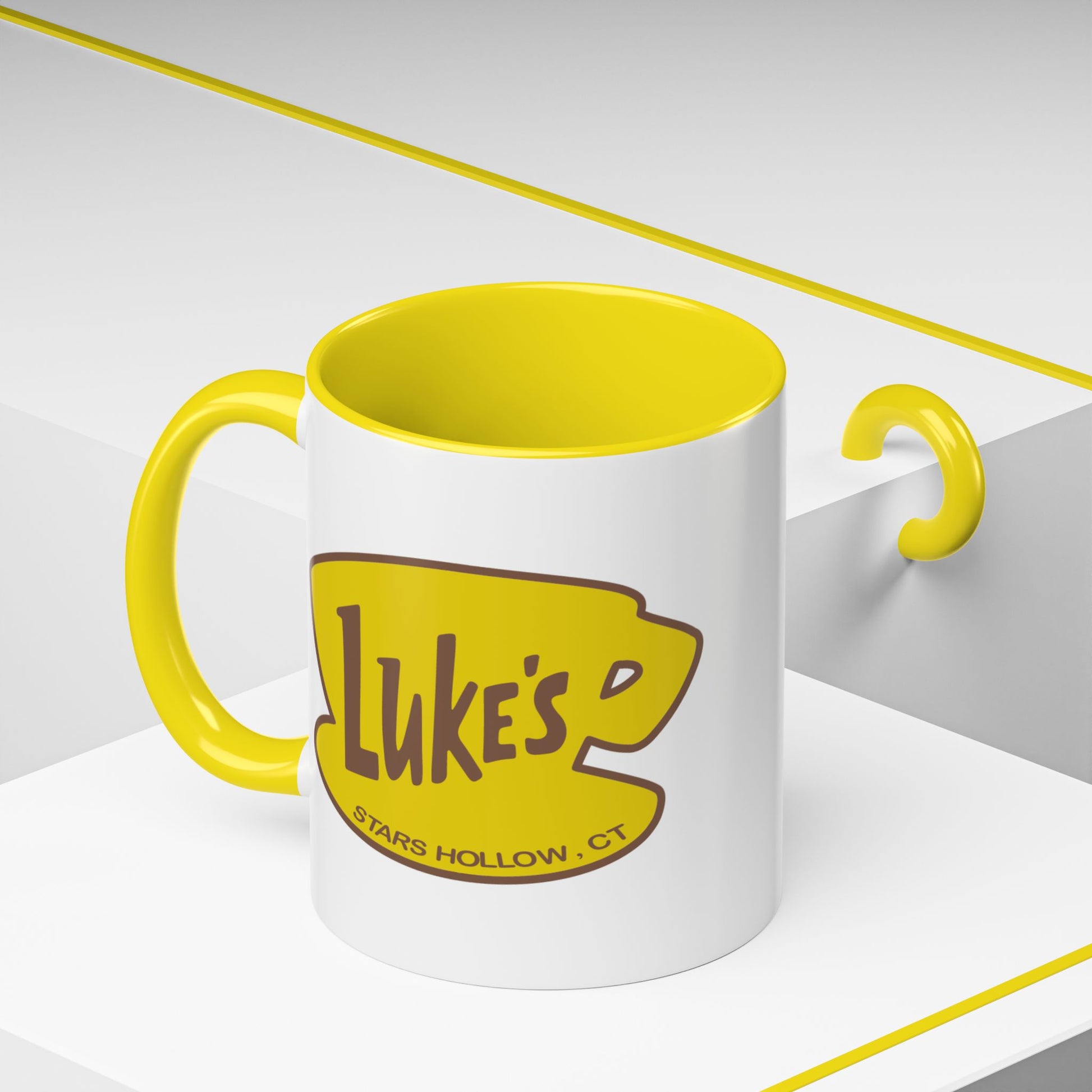 Angled view of 11 oz White ceramic mug with yellow handle and Luke’s Diner logo from Gilmore Girls printed on both sides.