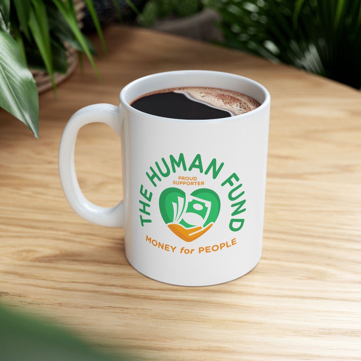 White mug with 'The Human Fund' logo on a wooden table