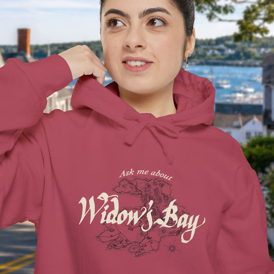 Woman wearing Crimson garment-dyed Widow's Bay hoodie with vintage island map design and Ask Me About Widow's Bay text