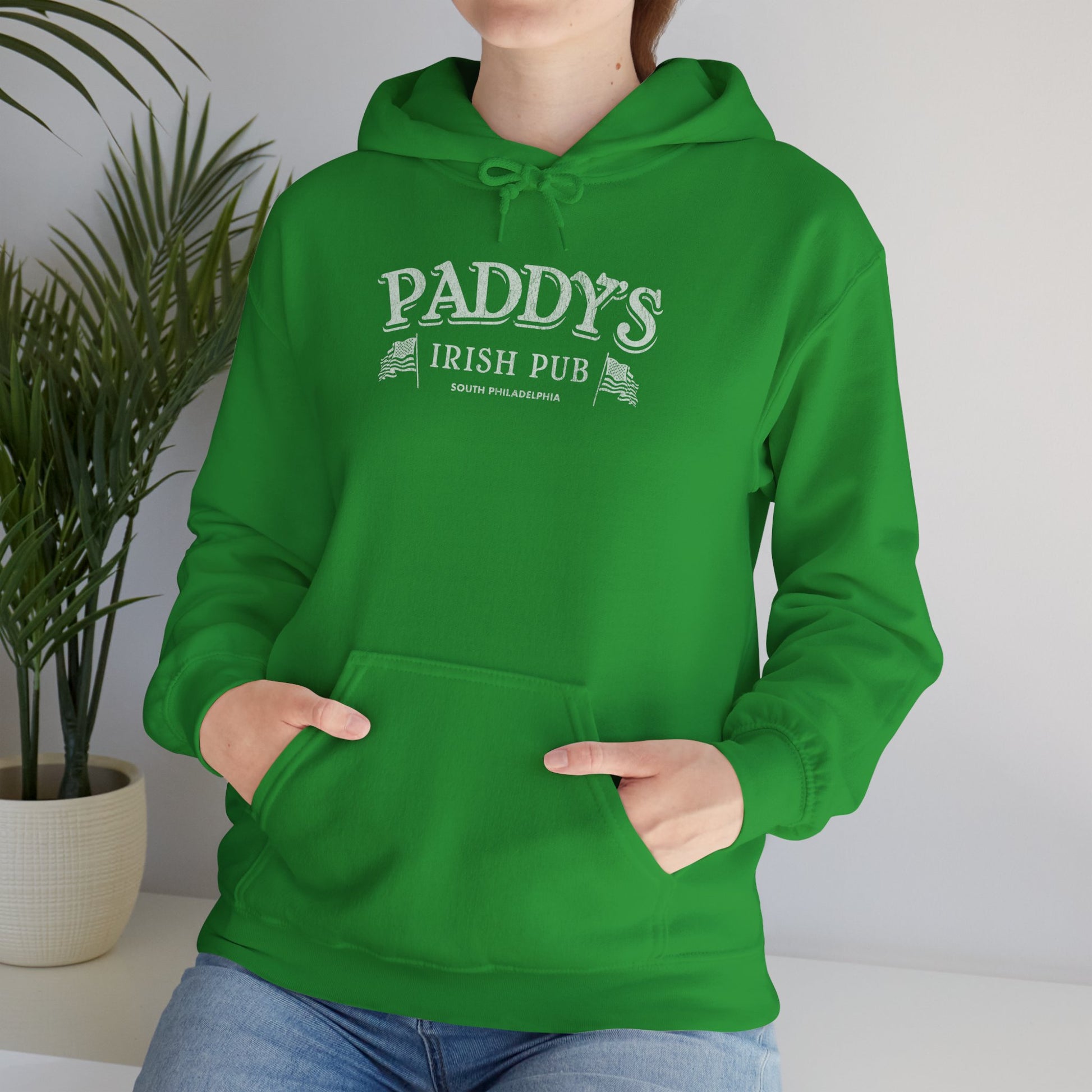 Woman wearing green Hoodie Sweatshirt with the Paddy's Pub logo graphic from the TV Show Its Always Sunny in Philadelphia in a vintage style.