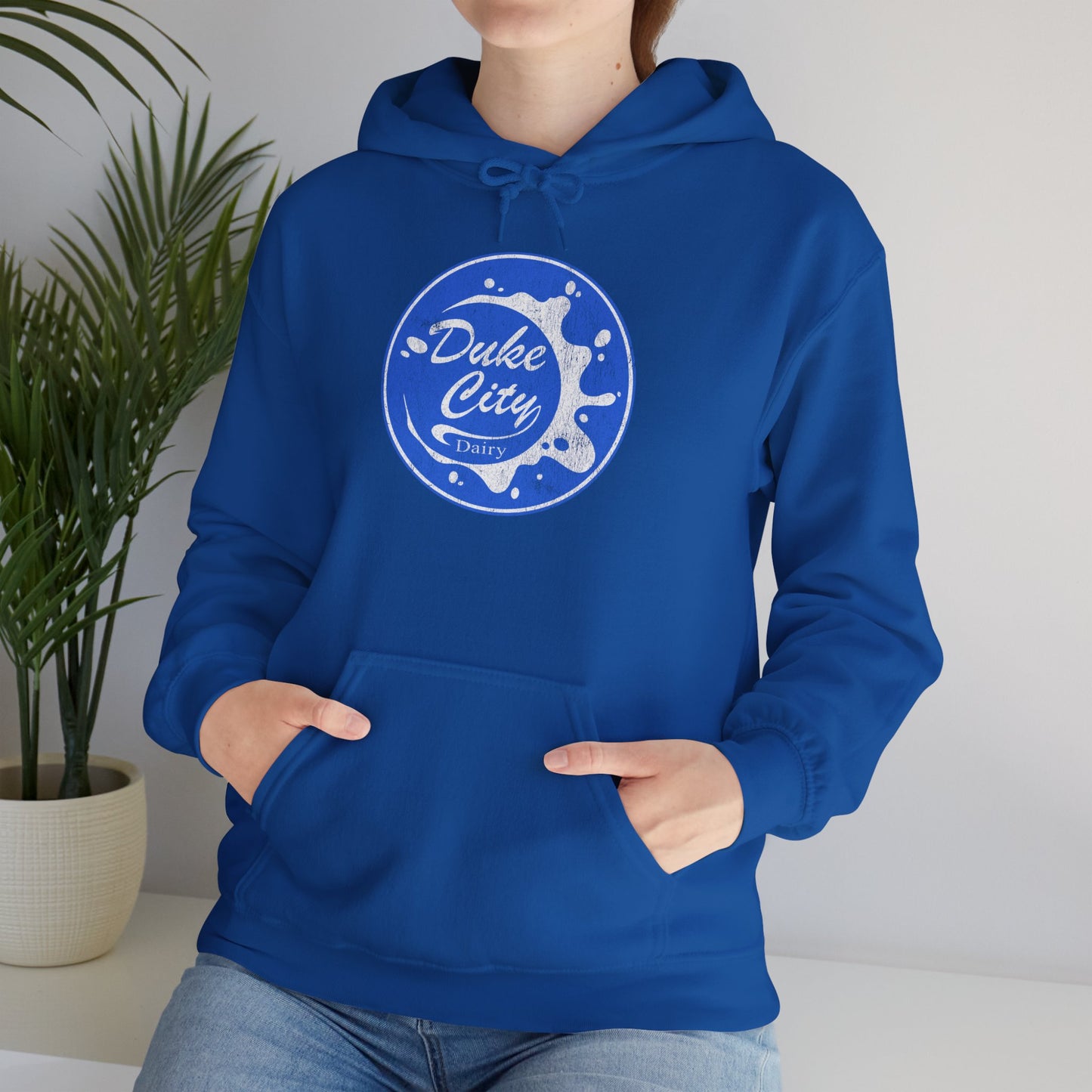 Woman wearing royal blue hoodie with 'Duke City Dairy' logo from Pluribus.