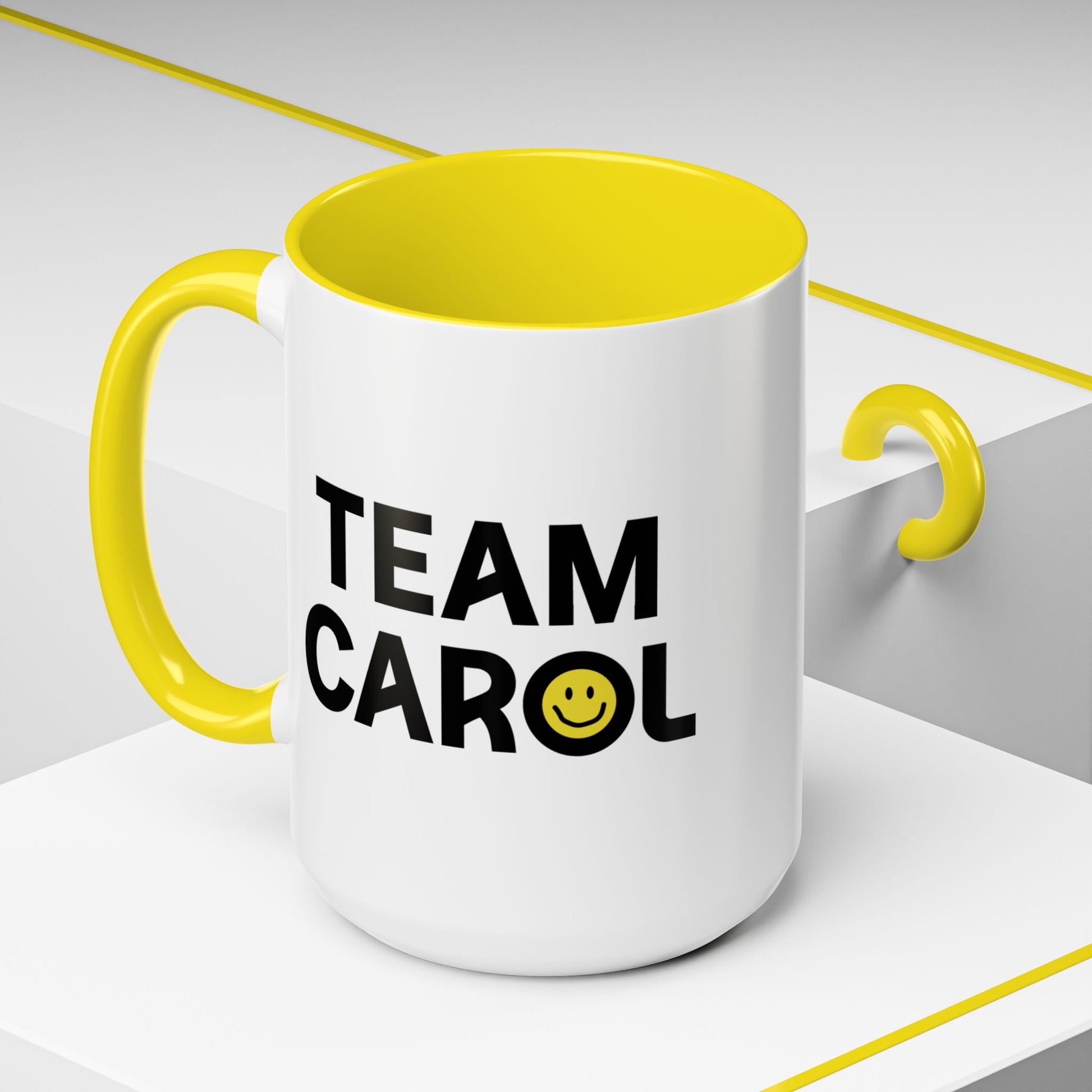 Angled view of 15 oz ceramic accent mug with yellow handle and interior, TEAM CAROL text and smiley face from Pluribus