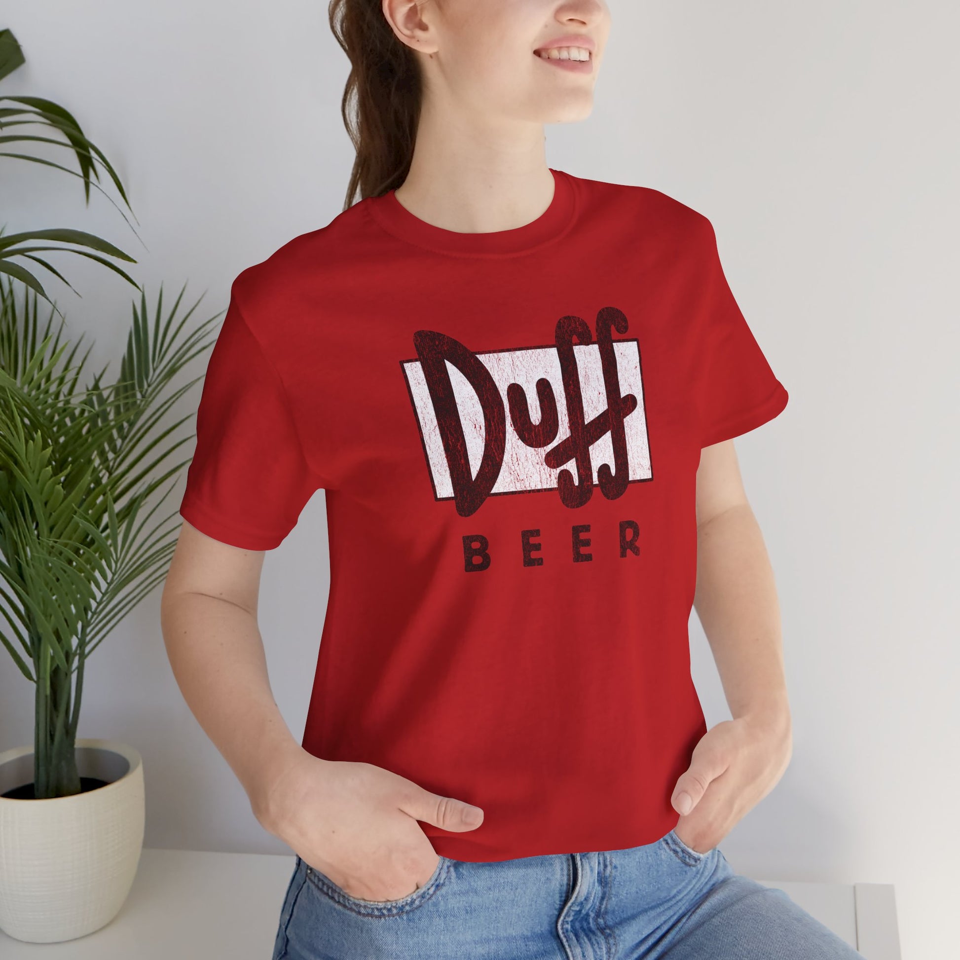 Woman wearing red t-shirt featuring the Duff Beer logo from the TV Show The Simpsons in vintage distressed style.