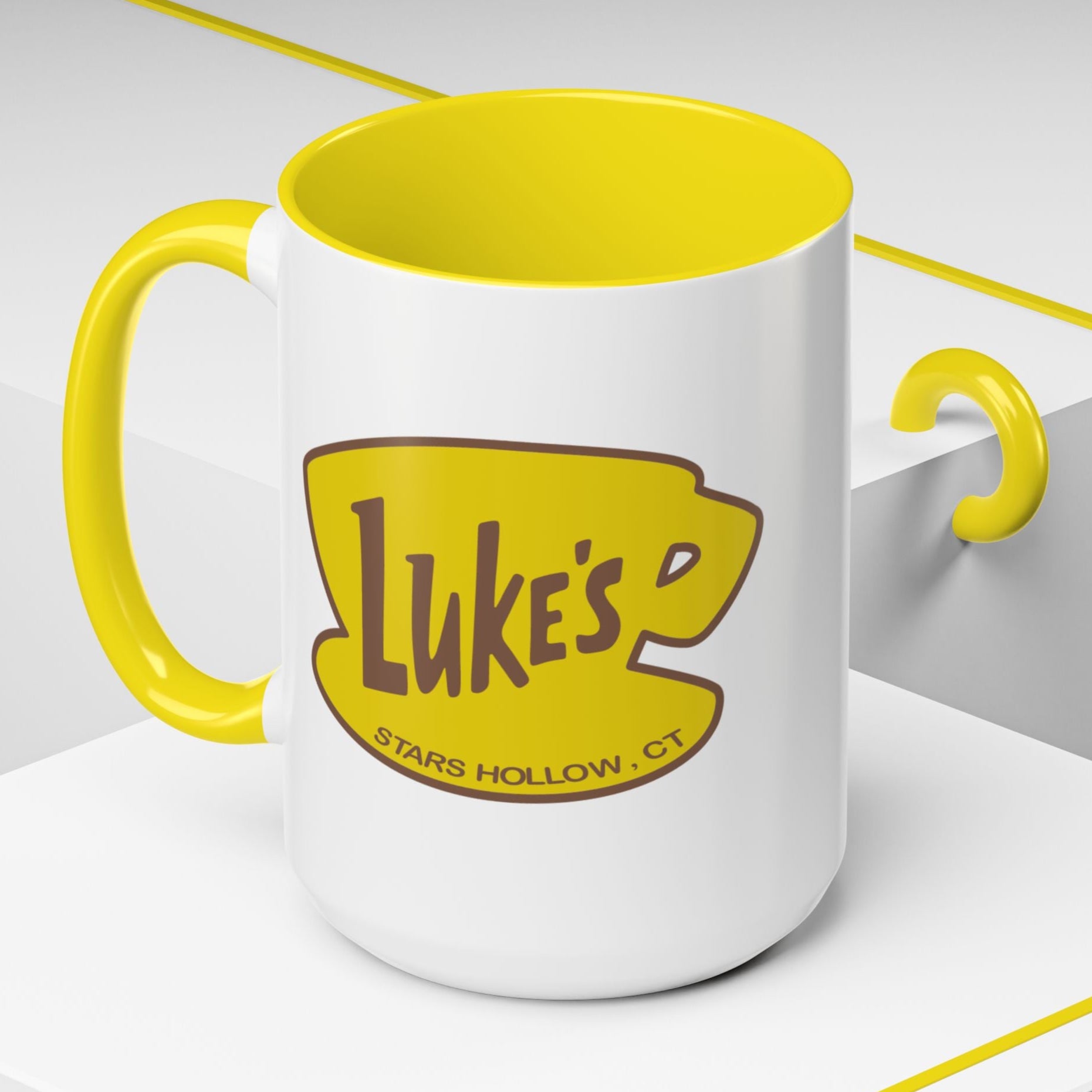 Angled view of 15 oz White ceramic mug with yellow handle and Luke’s Diner logo from Gilmore Girls printed on both sides.