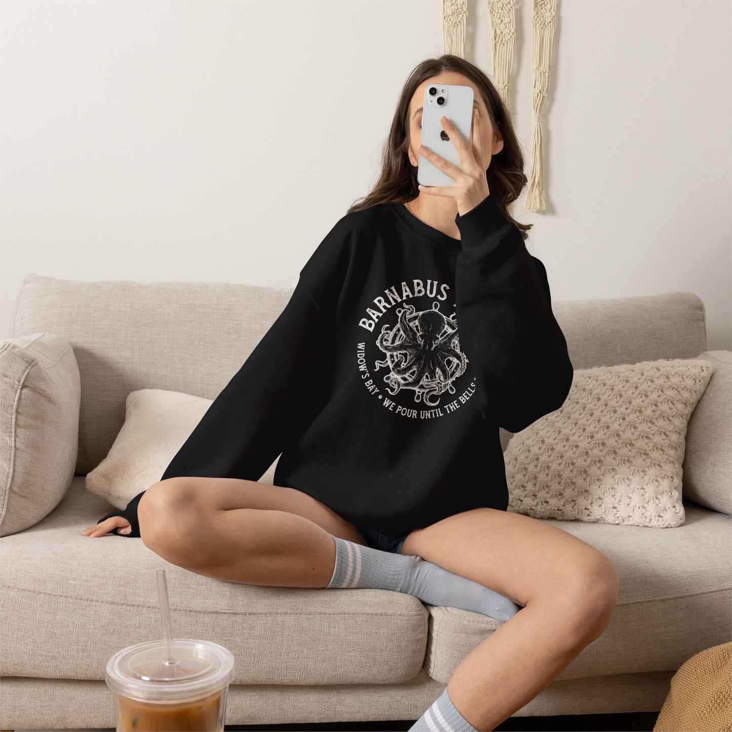 Woman wearing black crewneck sweatshirt with vintage Barnabus Tavern graphic from Widow's Bay TV show octopus design