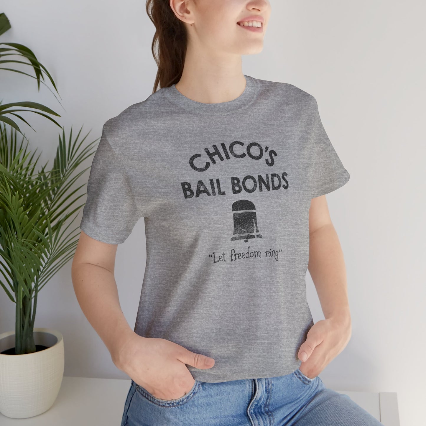 female wearing grey t-shirt with distressed Chico’s Bail Bonds logo and “Let freedom ring” slogan from The Bad News Bears movie.