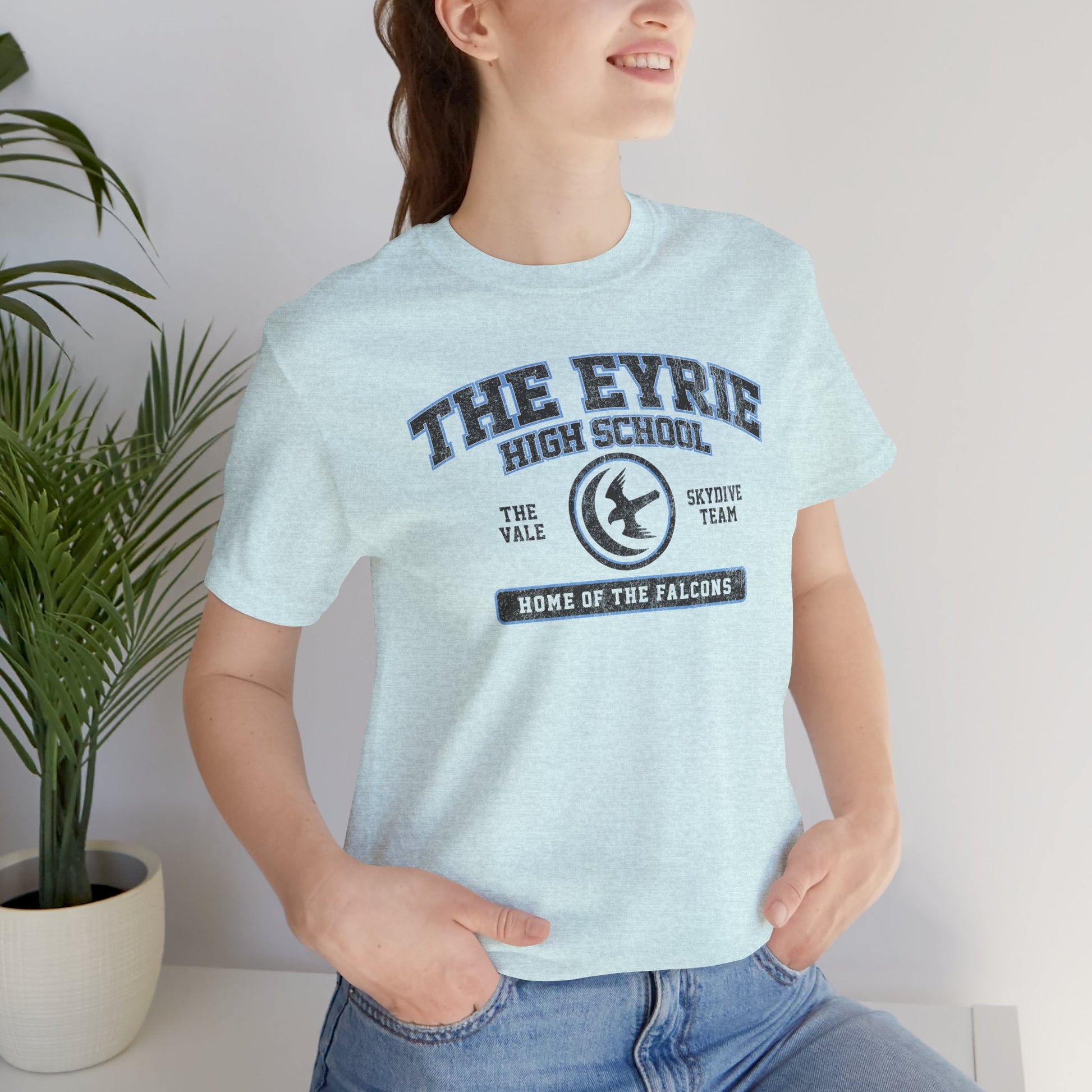 Woman wearing heather prism ice blue The Eyrie High School t-shirt with vintage falcon moon door graphic inspired by Game of Thrones and the Vale.
