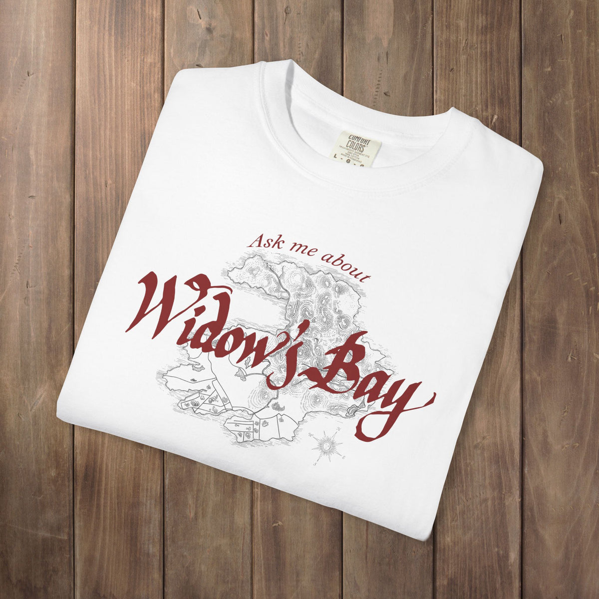 Folded White Comfort Colors tee with a vintage island map and antique "Ask Me About Widow's Bay" type from the Apple TV show