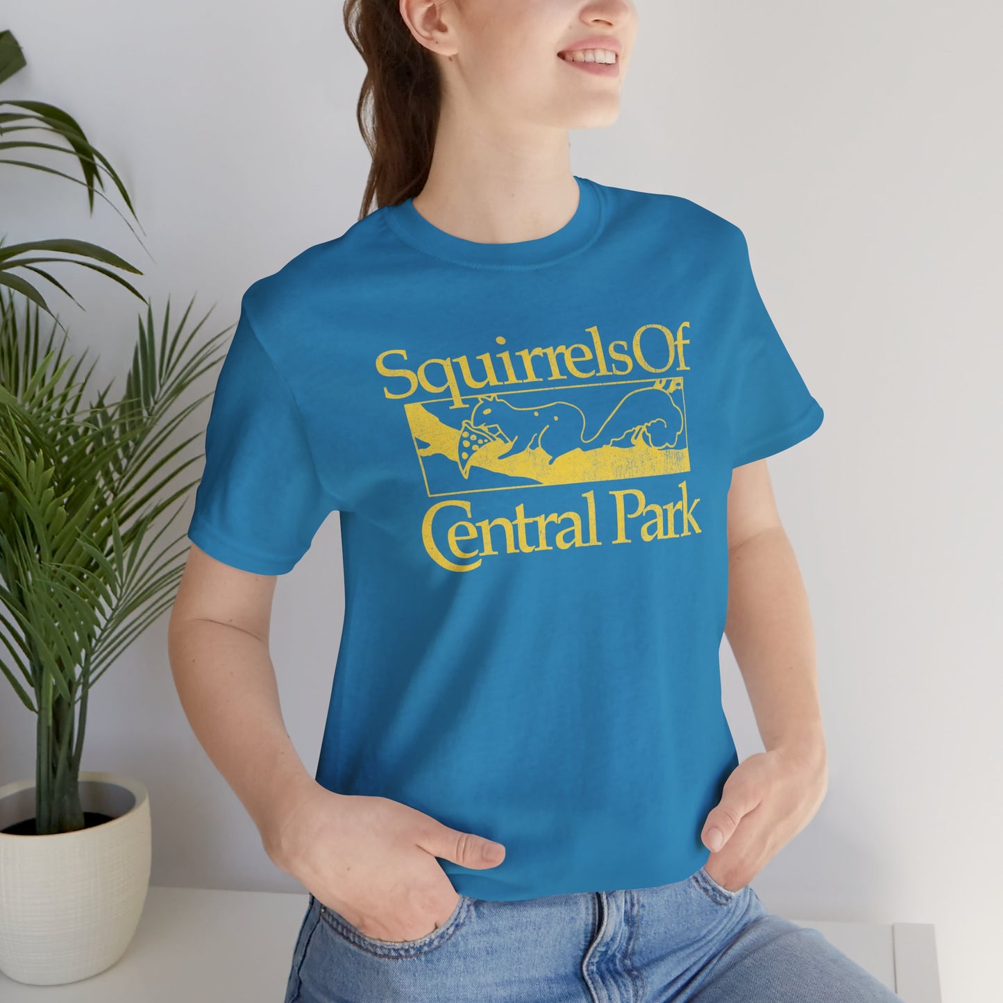 Woman wearing aqua blue unisex t-shirt with distressed “Squirrels of Central Park” graphic, worn by Eva Garvey in the show Bad Sisters.