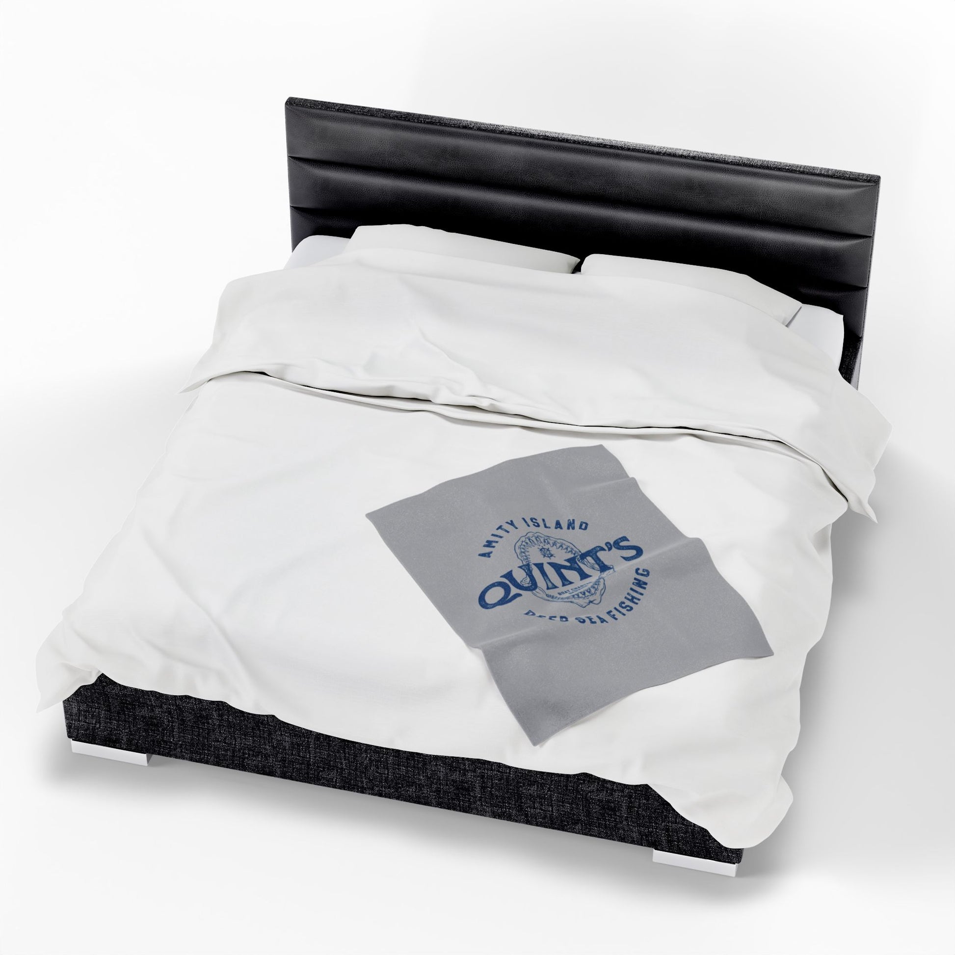 30x40 Gray velveteen plush blanket with vintage blue Quint’s Deep Sea Fishing logo inspired by Jaws, laid on a queen sized bed.