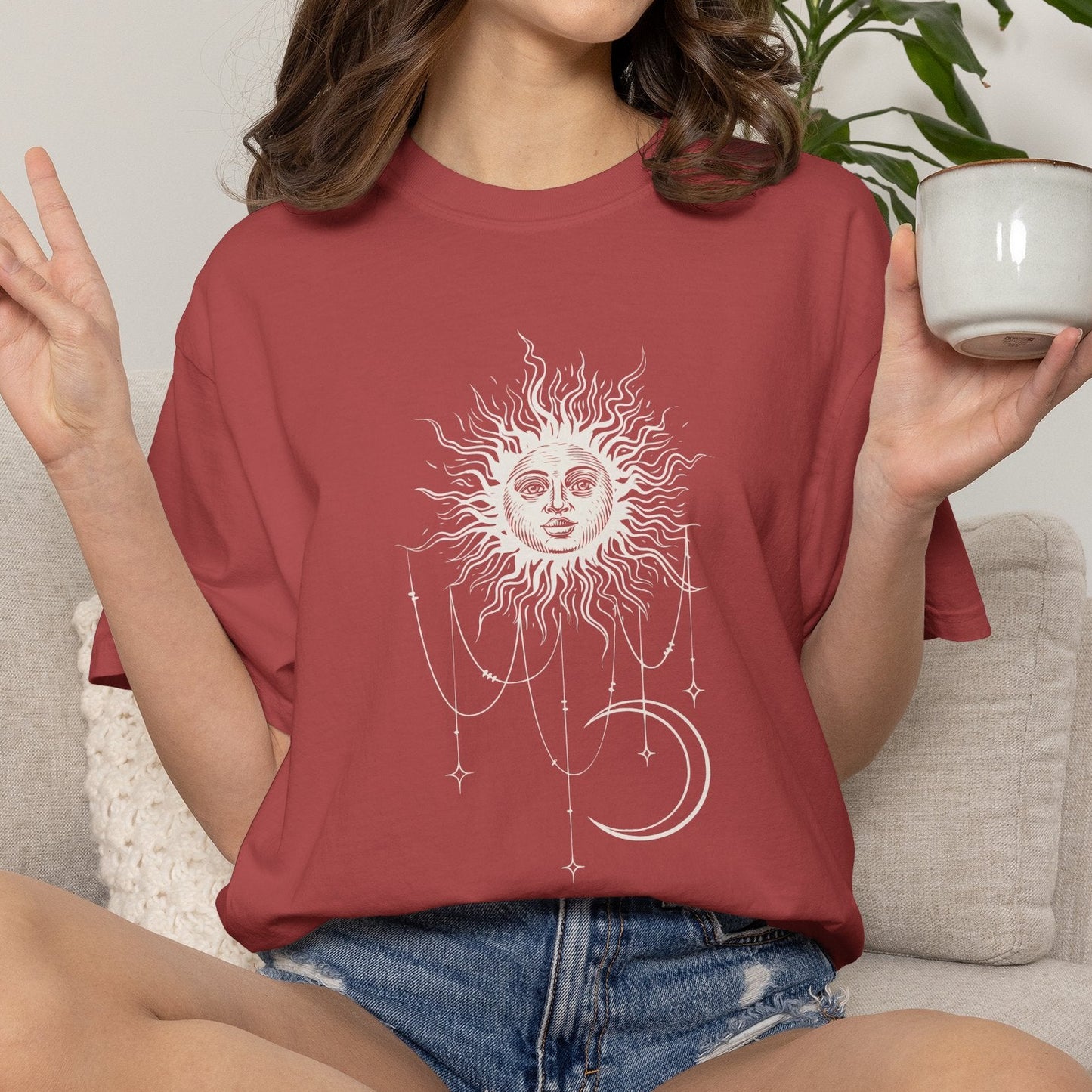 Person wearing Crimson red Comfort Colors tee with a celestial sun and crescent moon design, worn by Patricia in Widow's Bay S1E8