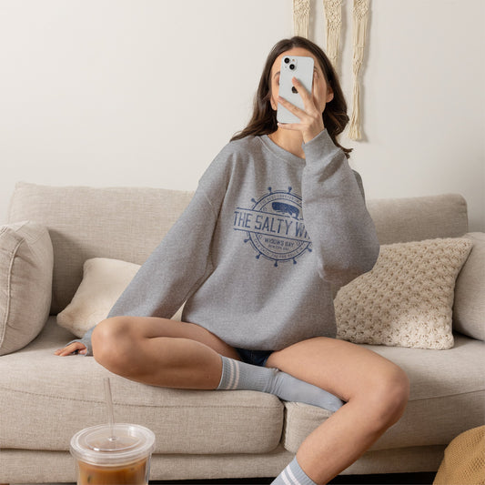 Woman wearing Heather Sport Grey Gildan crewneck sweatshirt with the distressed Salty Whale maritime crest logo from TV show Widow's Bay