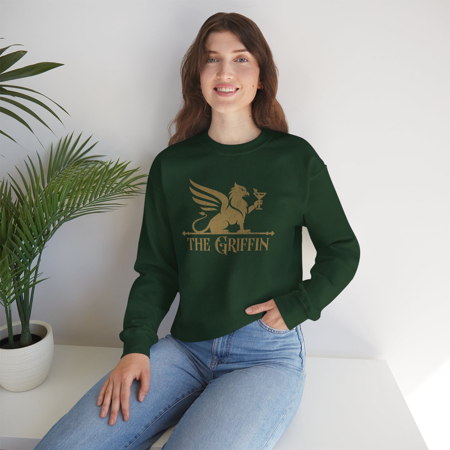 Woman wearing green crewneck sweatshirt with vintage distressed The Griffin Bar logo graphic inspired by New Girl