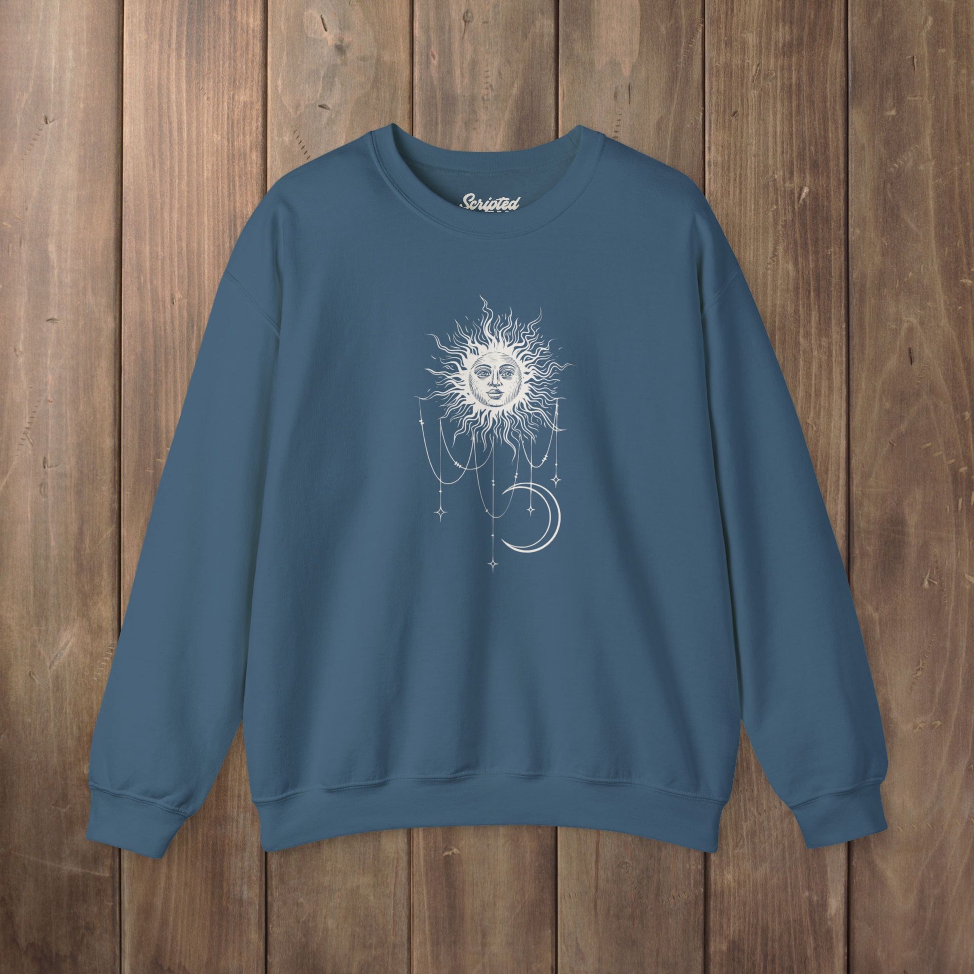 Indigo blue crewneck sweatshirt with boho celestial sun face, stars, and crescent moon design worn by Patricia in Widow's Bay