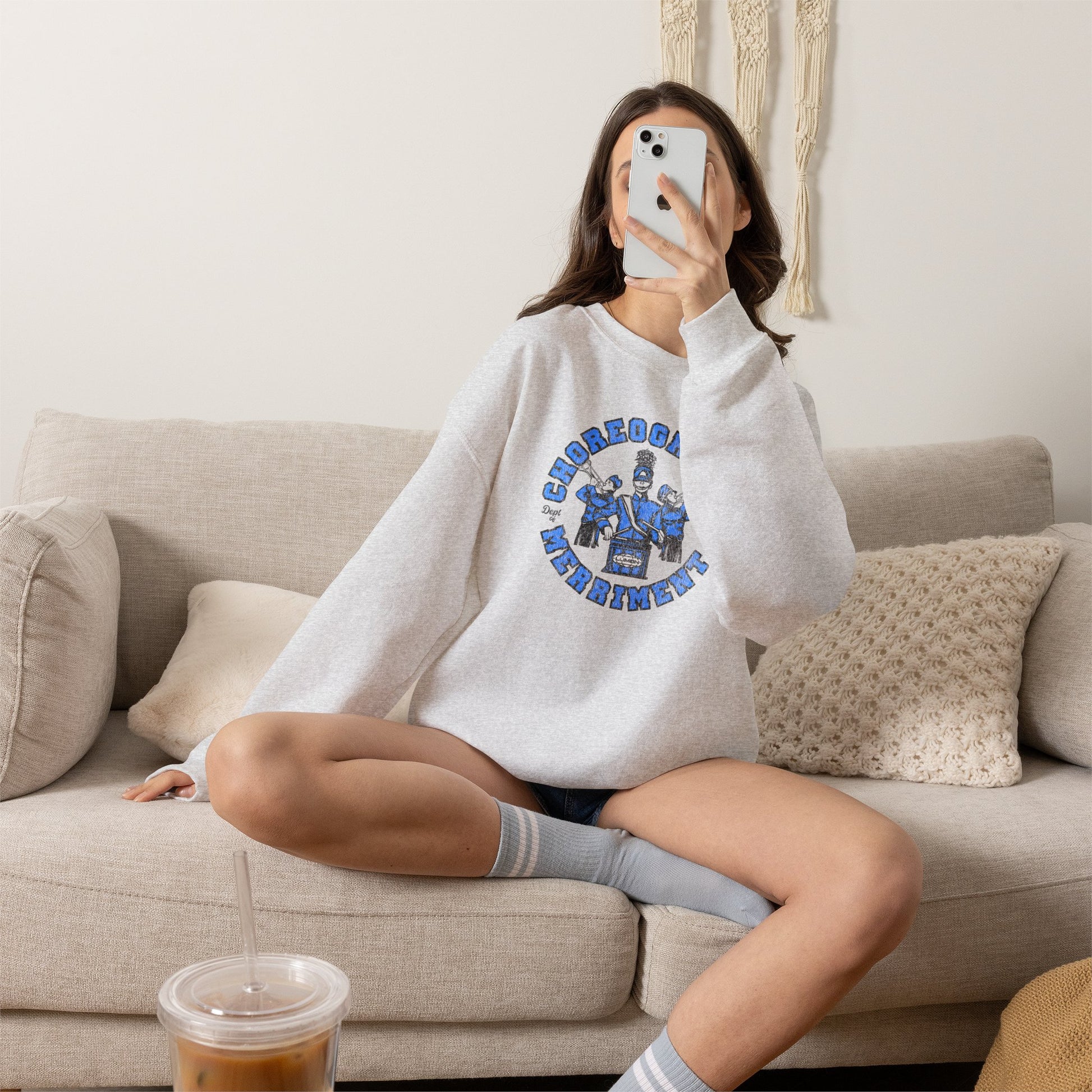Woman wearing ash crewneck sweatshirt with vintage Lumon Choreography and Merriment marching band art from Severance.